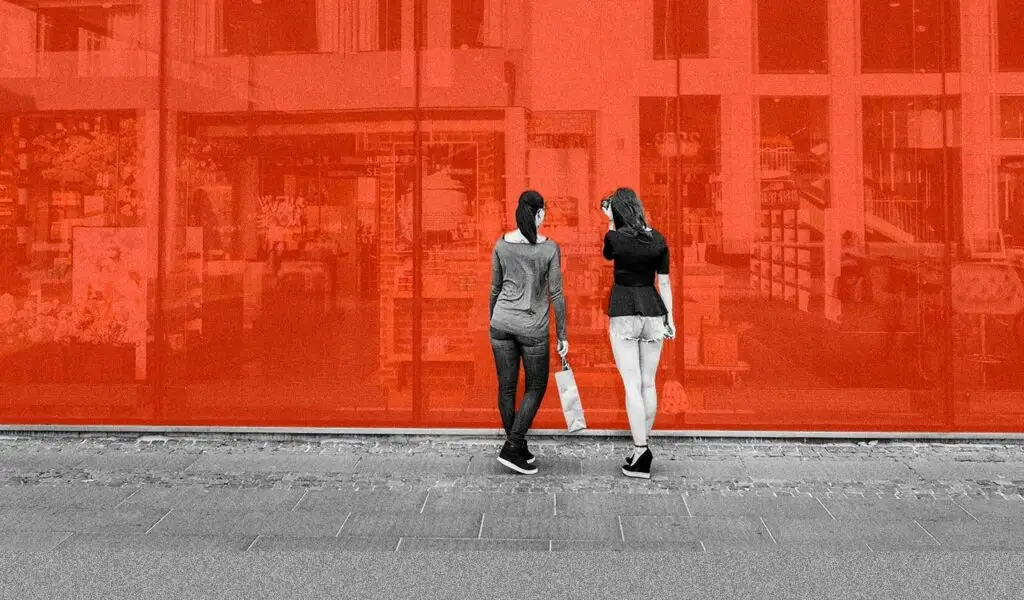 two women standing next to a wall